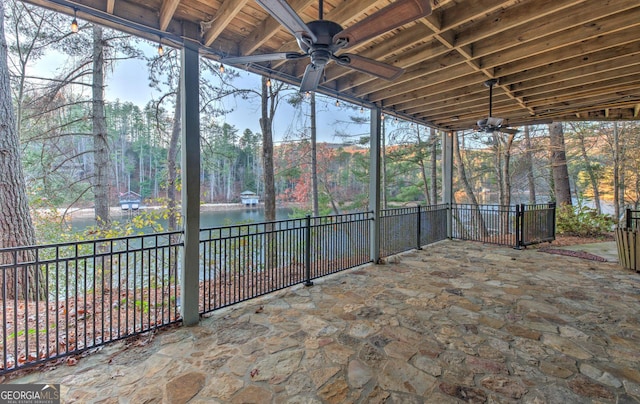 unfurnished sunroom featuring ceiling fan and a water view