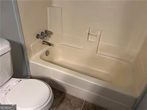 bathroom featuring tile patterned flooring, tub / shower combination, and toilet