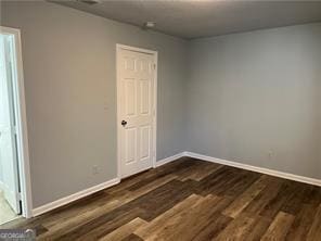 empty room with dark hardwood / wood-style flooring