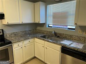 kitchen featuring dark stone counters, sink, range hood, white cabinetry, and stainless steel appliances