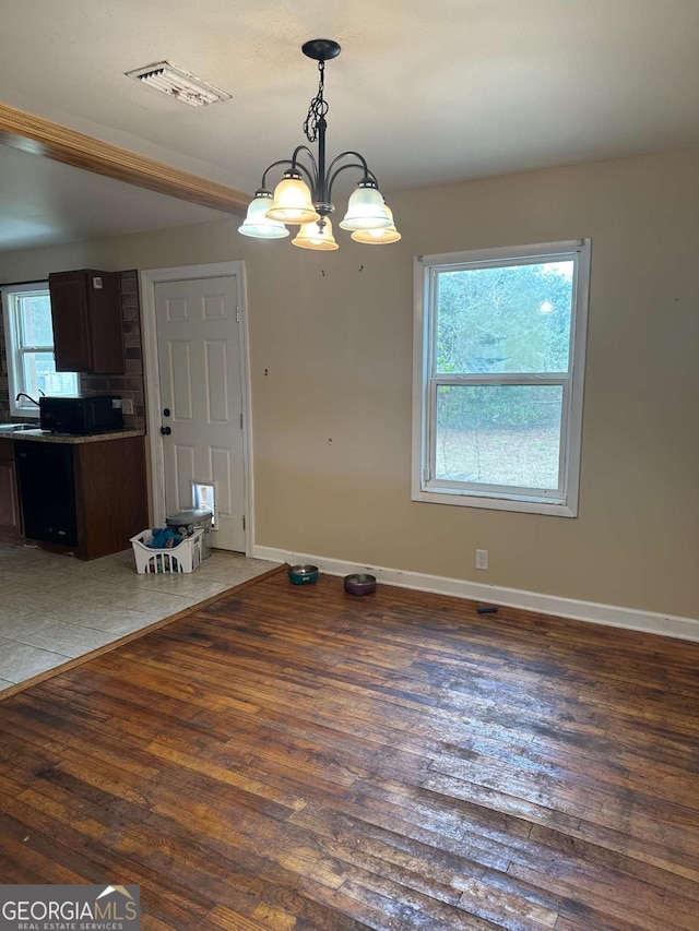 unfurnished dining area featuring dark wood-type flooring, a notable chandelier, and sink