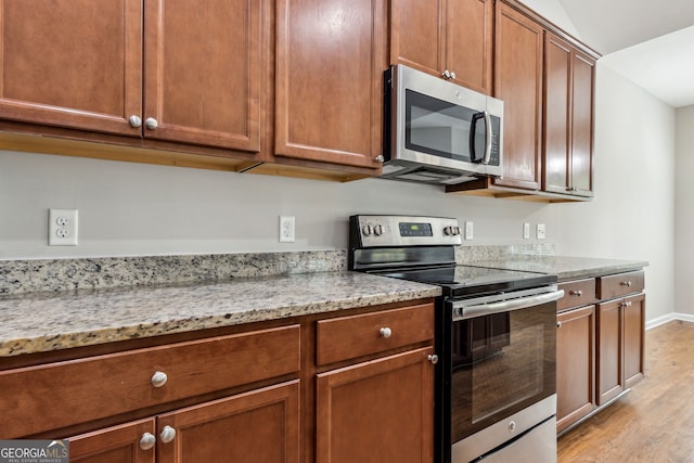 kitchen featuring light stone countertops, light wood-type flooring, and stainless steel appliances