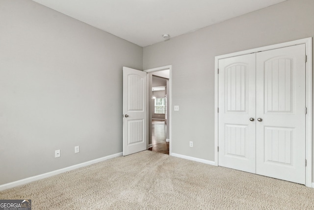 unfurnished bedroom with light colored carpet and a closet