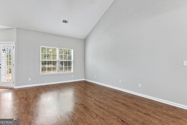 spare room featuring vaulted ceiling, plenty of natural light, and dark wood-type flooring