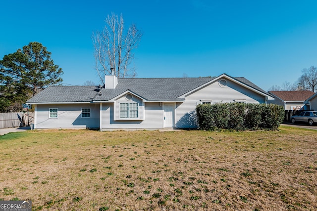 view of front of property with a chimney, fence, a front lawn, and roof with shingles