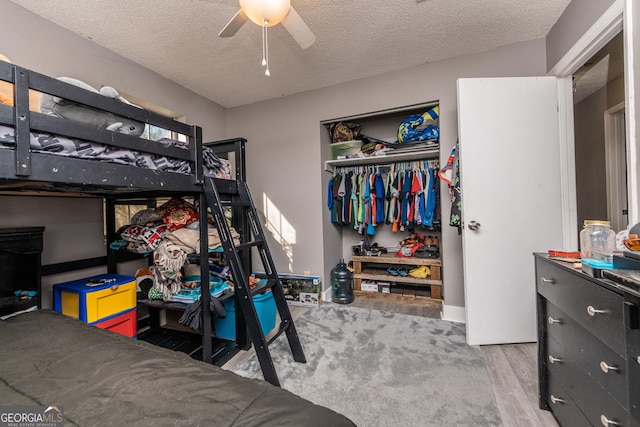 bedroom featuring a textured ceiling, ceiling fan, a closet, and wood finished floors