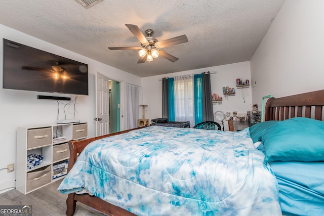 bedroom featuring a textured ceiling, wood finished floors, and a ceiling fan