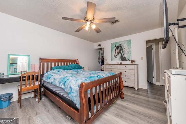 bedroom with visible vents, ceiling fan, light wood-style flooring, and a textured ceiling