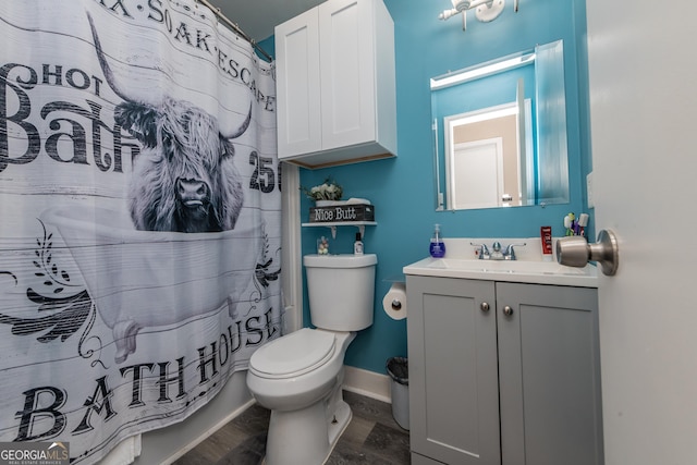 bathroom with a shower with shower curtain, toilet, vanity, wood finished floors, and baseboards