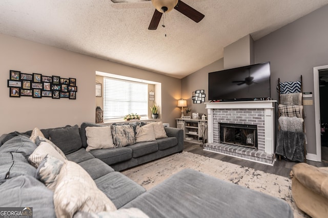 living area with a fireplace, lofted ceiling, a ceiling fan, a textured ceiling, and wood finished floors