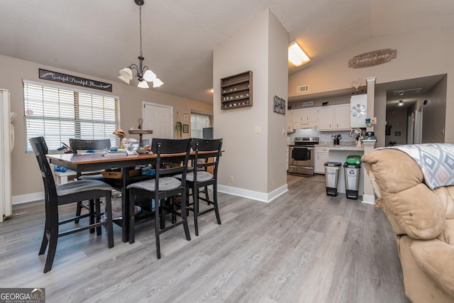 dining room featuring baseboards, visible vents, lofted ceiling, light wood-style floors, and a chandelier