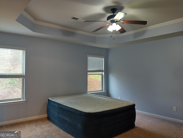 carpeted bedroom featuring a raised ceiling, ceiling fan, and ornamental molding