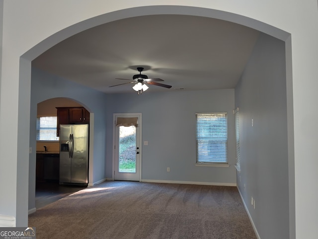 spare room featuring ceiling fan, sink, and dark colored carpet