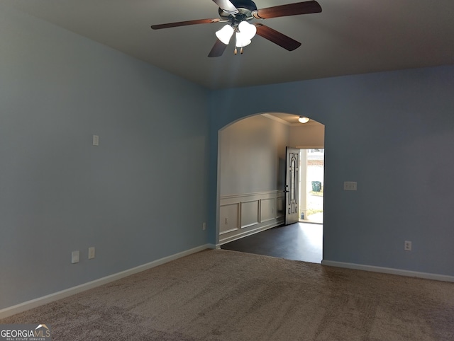 spare room featuring ceiling fan and dark carpet