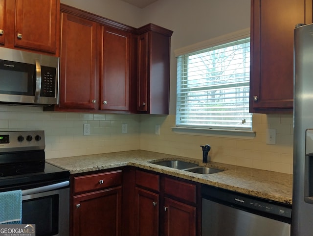 kitchen with decorative backsplash, light stone counters, sink, and appliances with stainless steel finishes