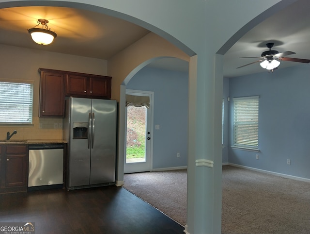 kitchen with appliances with stainless steel finishes, backsplash, dark carpet, ceiling fan, and sink