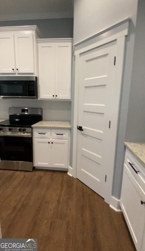 kitchen featuring dark hardwood / wood-style floors, light stone countertops, white cabinetry, and stainless steel appliances