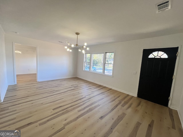 entryway with light hardwood / wood-style floors and a notable chandelier