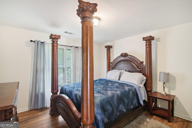 bedroom with dark hardwood / wood-style flooring and ornate columns