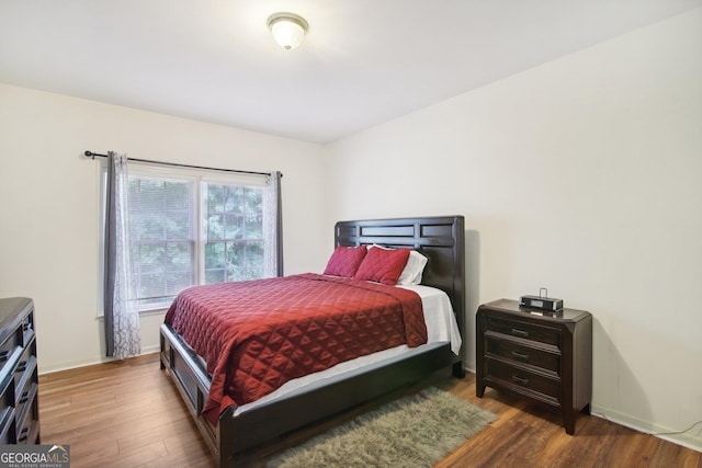 bedroom with dark hardwood / wood-style floors and multiple windows