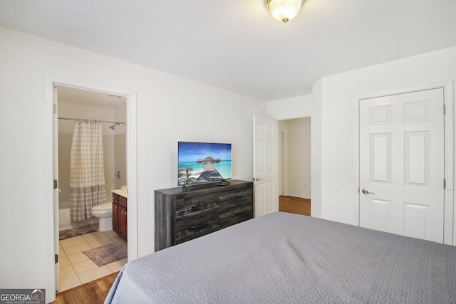 bedroom with light tile patterned floors and ensuite bath