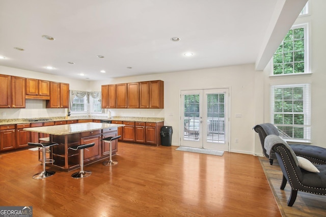 kitchen featuring stainless steel gas stovetop, a breakfast bar, french doors, light wood-type flooring, and a kitchen island