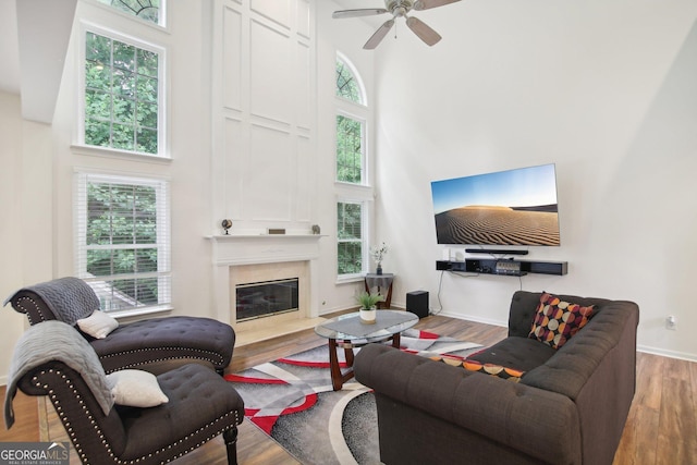 living room featuring a premium fireplace, hardwood / wood-style floors, and a high ceiling