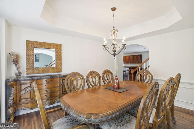 dining room with a raised ceiling, dark hardwood / wood-style flooring, and a notable chandelier