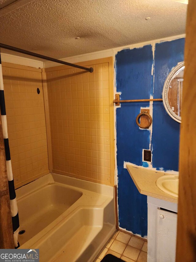 bathroom featuring tile patterned floors, vanity,  shower combination, and a textured ceiling