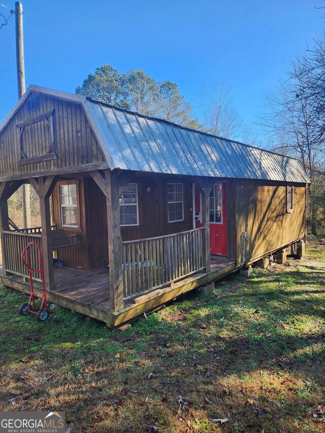 back of house featuring covered porch and a yard