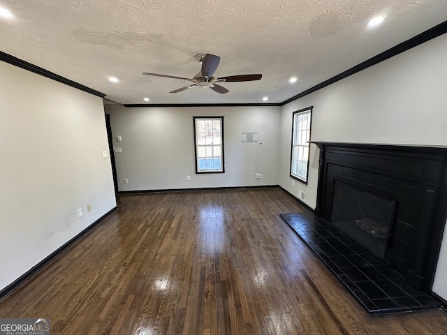 unfurnished living room featuring a tile fireplace, a textured ceiling, dark wood-type flooring, and ornamental molding