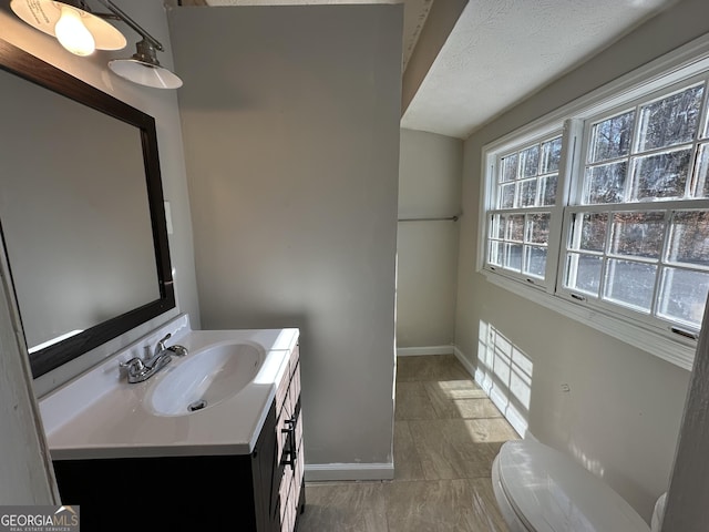 bathroom featuring a textured ceiling, vanity, and toilet