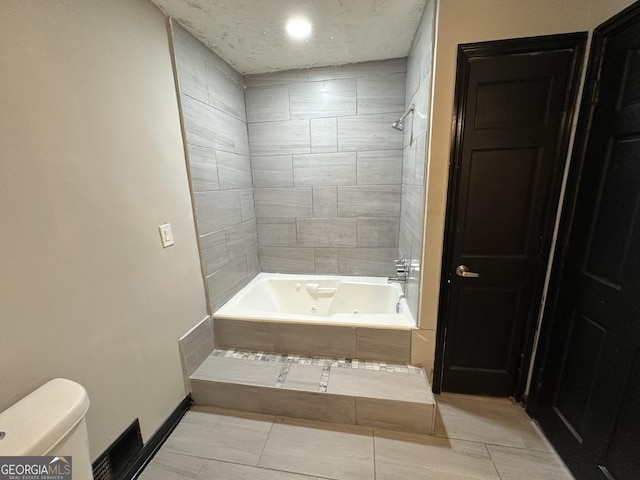 bathroom with tile patterned flooring, tiled shower / bath combo, and toilet