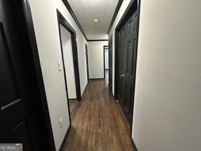 hall featuring crown molding, dark wood-type flooring, and a textured ceiling