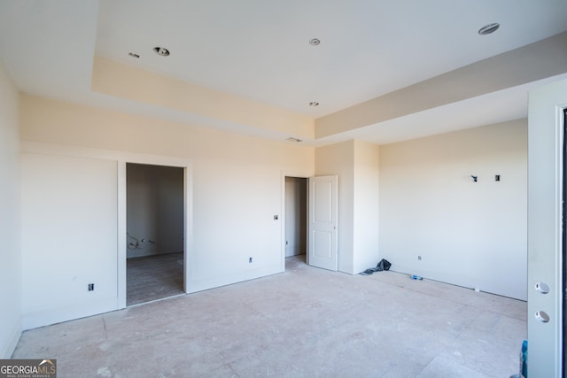 unfurnished bedroom featuring a raised ceiling and ensuite bath