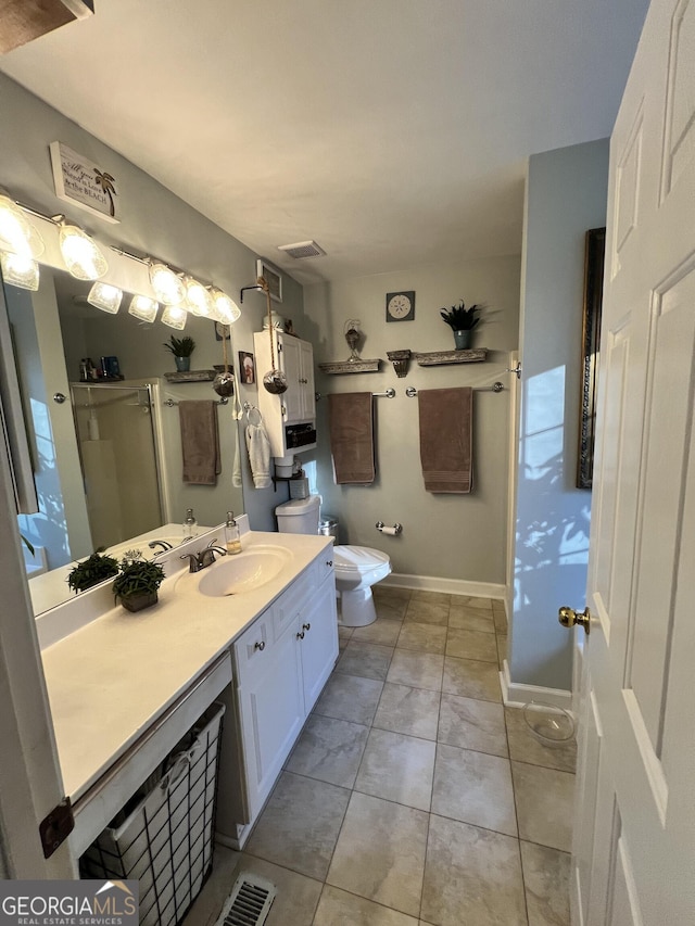 bathroom with vanity, toilet, tile patterned floors, and walk in shower