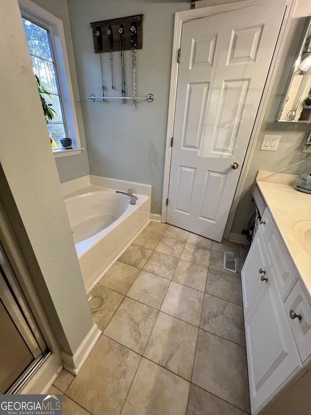 bathroom with tile patterned flooring, vanity, and a tub