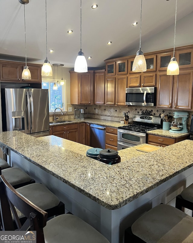 kitchen with lofted ceiling, appliances with stainless steel finishes, hanging light fixtures, and tasteful backsplash