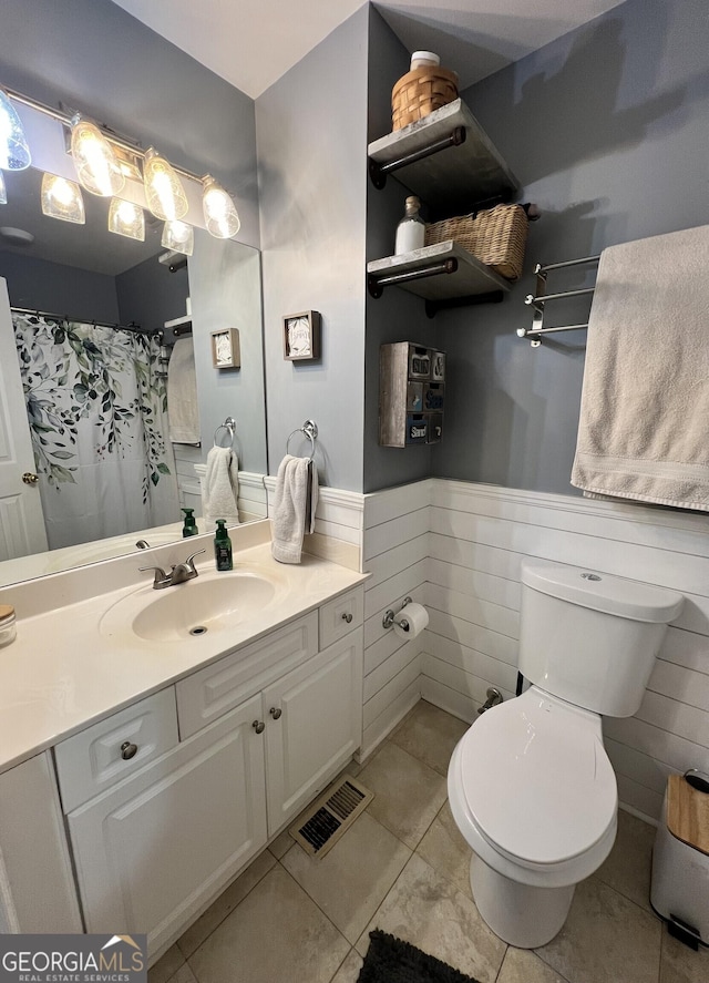 bathroom with toilet, tile patterned flooring, tile walls, and vanity