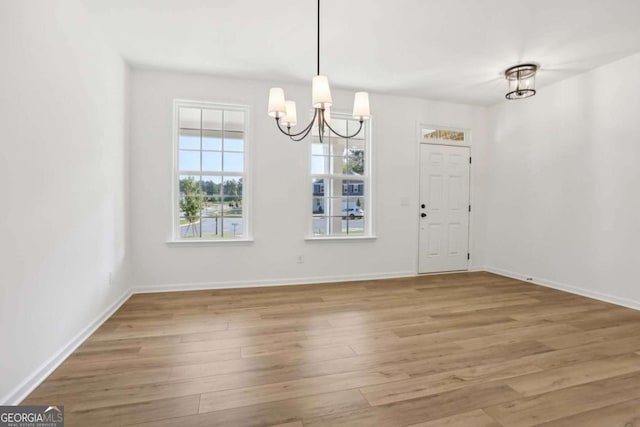 unfurnished dining area with hardwood / wood-style flooring and a chandelier