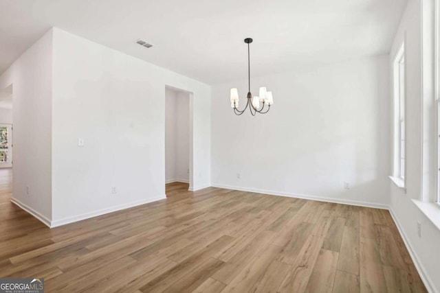 empty room featuring light hardwood / wood-style floors and a notable chandelier