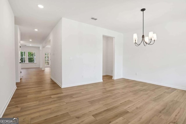 empty room featuring light hardwood / wood-style floors and an inviting chandelier