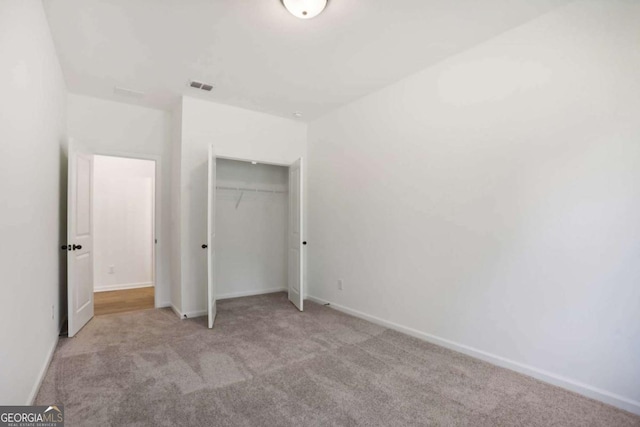 unfurnished bedroom featuring a closet and light colored carpet