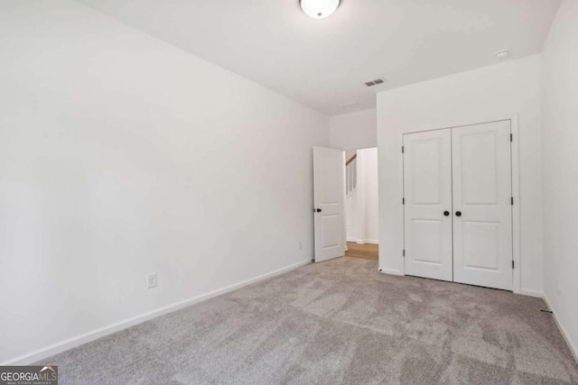 unfurnished bedroom featuring light carpet and a closet