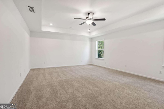 carpeted empty room featuring a tray ceiling and ceiling fan