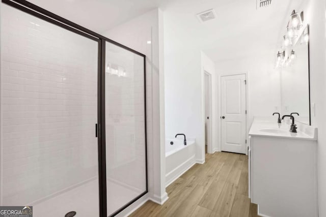 bathroom featuring vanity, hardwood / wood-style floors, and plus walk in shower