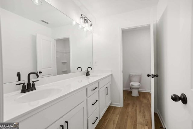 bathroom featuring wood-type flooring, vanity, and toilet