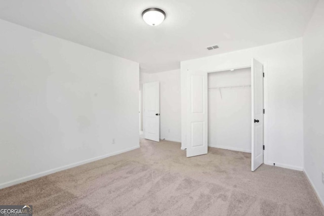 unfurnished bedroom with light carpet and a closet