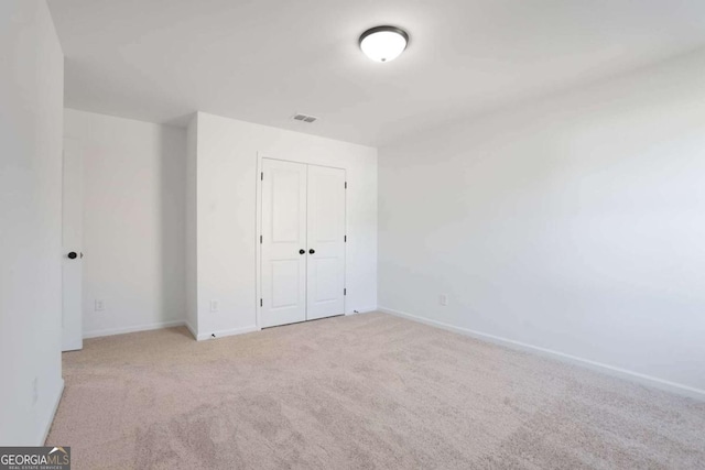 unfurnished bedroom featuring light carpet and a closet