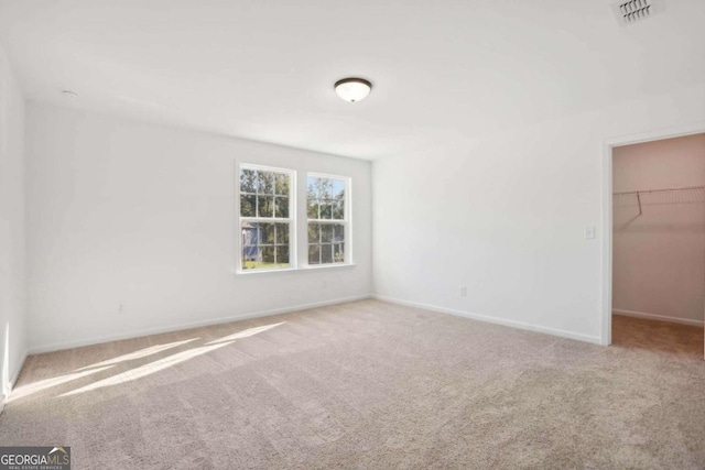 unfurnished bedroom featuring a spacious closet, carpet floors, and a closet